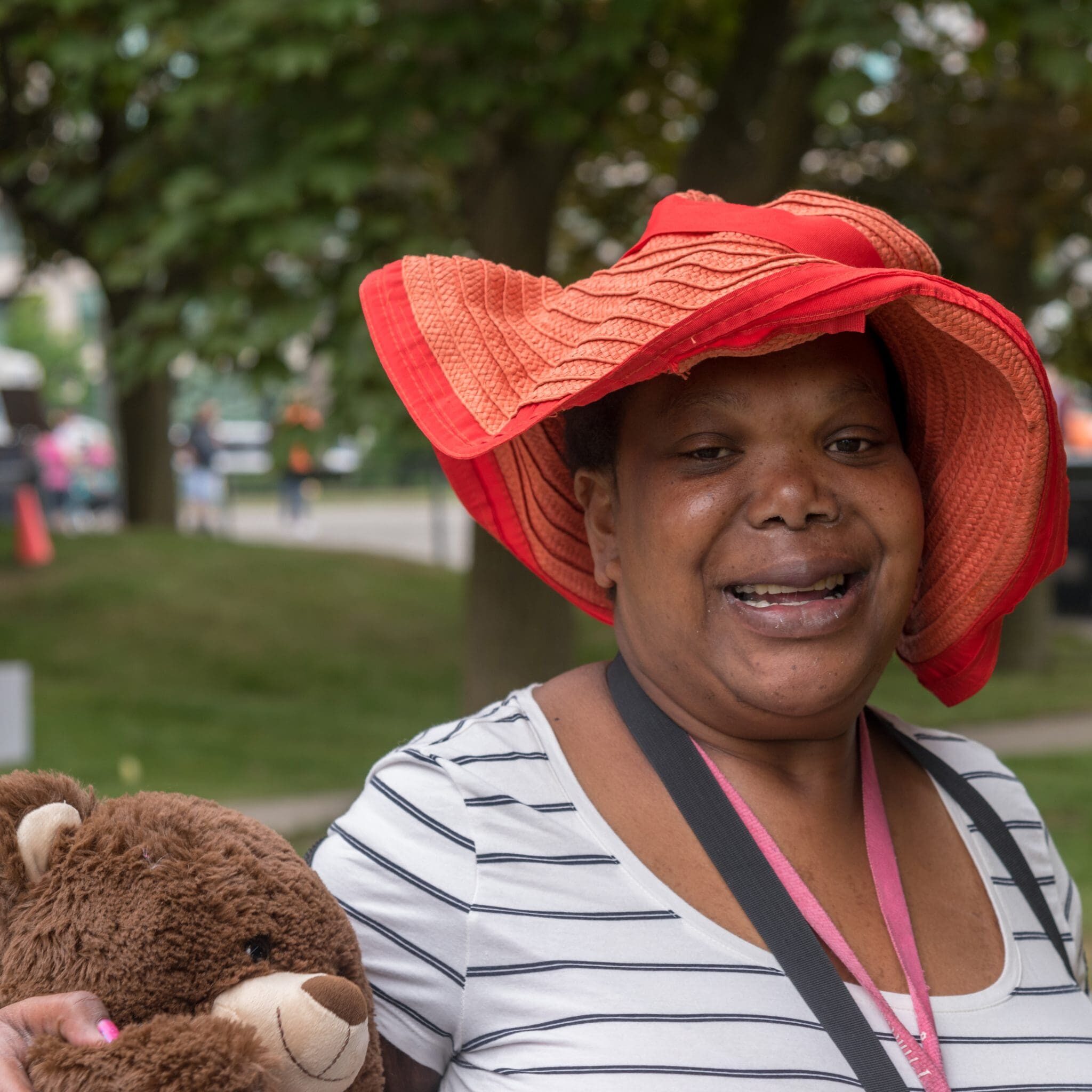 one woman wearing a big fun red hat and holding a teddy bear